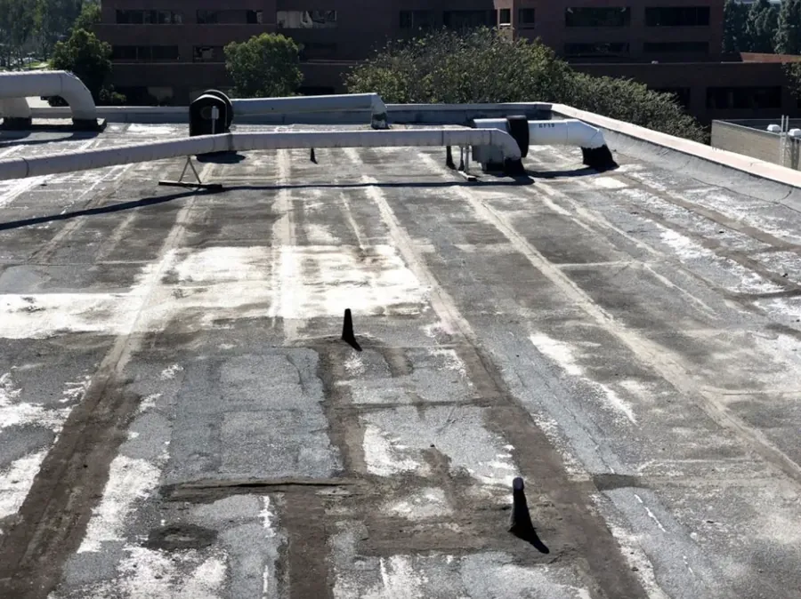 Worn flat roof covered in old patches and failing seams